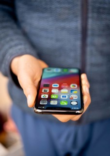 Hand haelt iPhone 11 Pro mit Homescreen