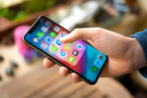Hand haelt iPhone 11 Pro mit App-Icons von Messenger Diensten und Sozialen Netzwerken