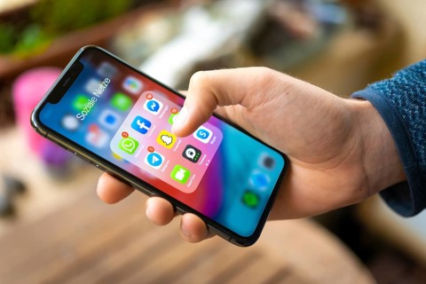 Hand haelt iPhone 11 Pro mit App-Icons von Messenger Diensten und Sozialen Netzwerken