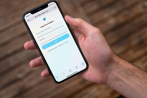 Hand haelt iPhone 11 Pro mit geoeffneter Twitter Website