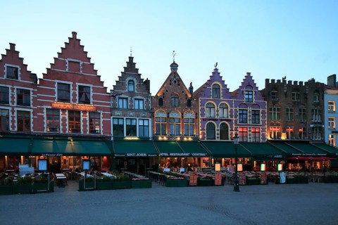 Market with residential buildings and restaurants on the north side of the square at dusk