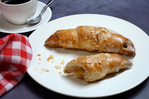 Almond croissant on plate with coffee cup
