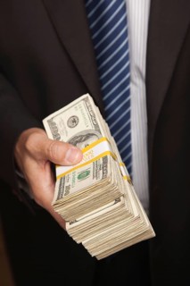 Businessman handing over stack of one hundred dollar bills