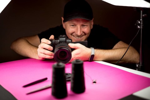 A photographer taking a photo of black tailoring accessories in the studio