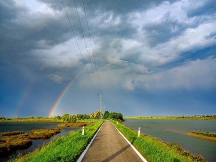 Clouds and rainbow over single lane road