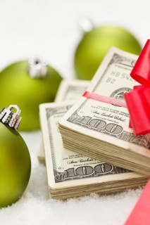 Stack of one hundred dollar bills with red bow near green christmas ornaments on snow flakes