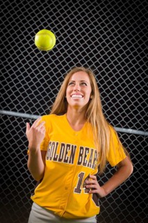 Young female softball player portrait with ball in the air
