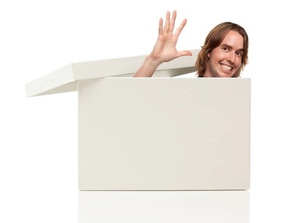 Young man waving his hand and popping his head from a blank white box isolated on a white background