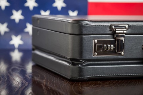 Black leather briefcase resting on table with american flag behind