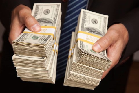Businessman handing over stacks of hundred dollar bills