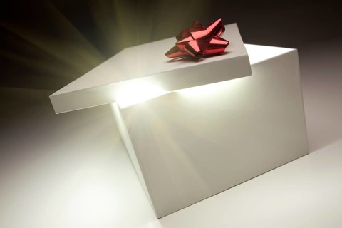 Gift box with red bow lid revealing very bright contents on a gradated background