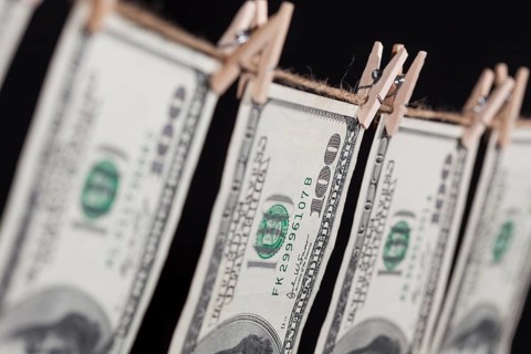 Hundred dollar bills hanging from a clothesline on a dark background