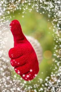 Woman in sweater with seasonal red mittens holding out a thumbs up sign with snow flakes border