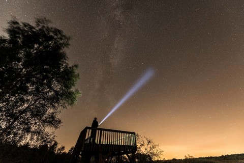 Stargazer under Milky Way with flashlight