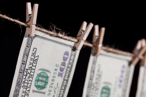 Hundred dollar bills hanging from a clothesline on a dark background