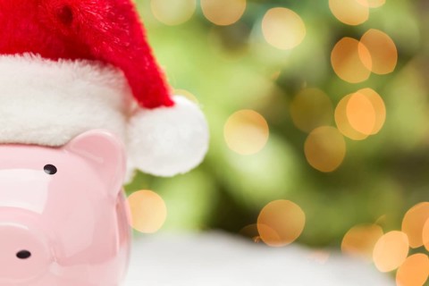 Pink piggy bank wearing red and white santa hat on snowflakes with abstract green and golden background