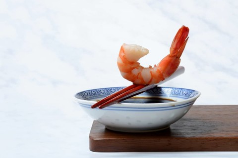 Cooked shrimp on chopsticks and shell with soy sauce