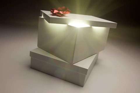Gift box with red bow lid revealing very bright contents on a gradated background