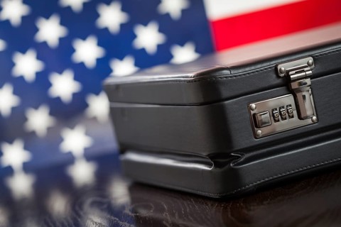 Black leather briefcase resting on table with american flag behind
