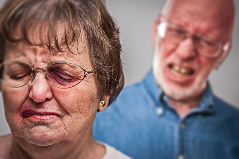 Battered and scared woman with ominous angry man behind