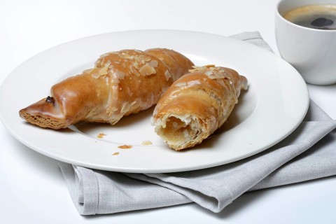 Almond croissant on plate with coffee cup