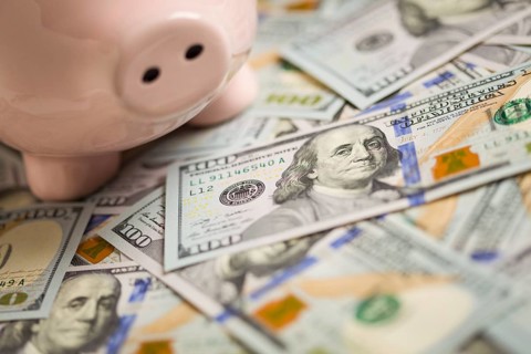 Piggy bank on stacks of newly designed one hundred dollar bills