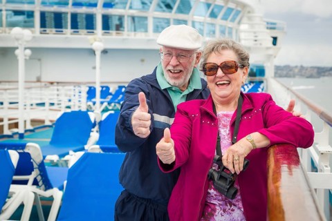 Happy senior couple with A thumbs up on the deck of A luxury passenger cruise ship