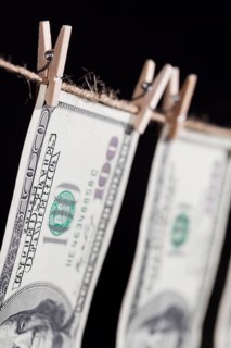Hundred dollar bills hanging from a clothesline on a dark background