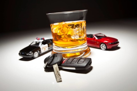 Highway patrol police and sports car next to alcoholic drink and keys under spot light