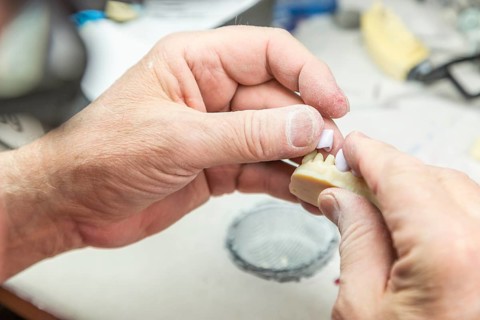 Male dental technician working on A 3D printed mold for tooth implants in the lab
