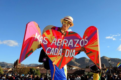 Stilt walkers with sign More hugs every day at parade on eve of Inti Raymi