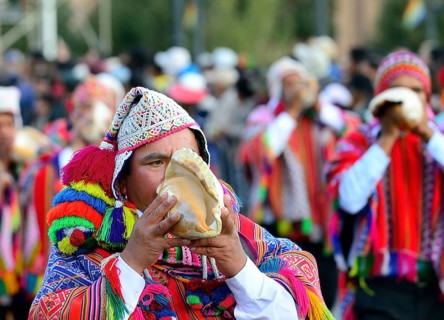Indigenous man blows conch shell during parade on eve of Inti Raymi
