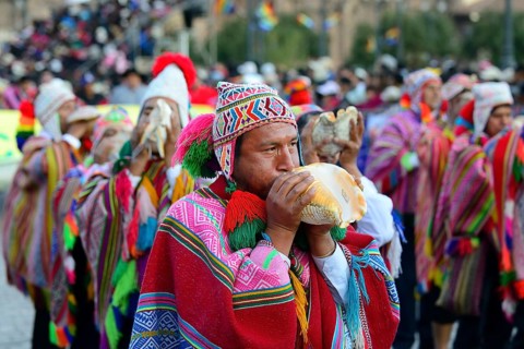 Indigenous man blows conch shell during parade on eve of Inti Raymi