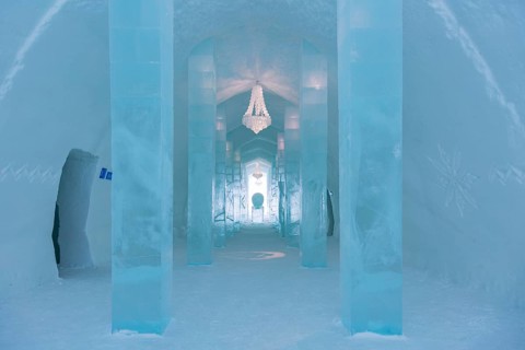 Long corridor with table and chandelier made of ice in the ice hotel of Jukkasjaervi