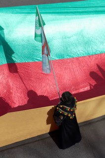 Kurdish woman demonstrates in front of the unfurled flag of the autonomous region of Kurdistan