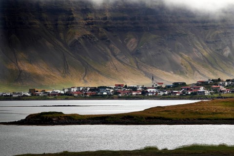 Fishing village on headland in front of mountain scenery