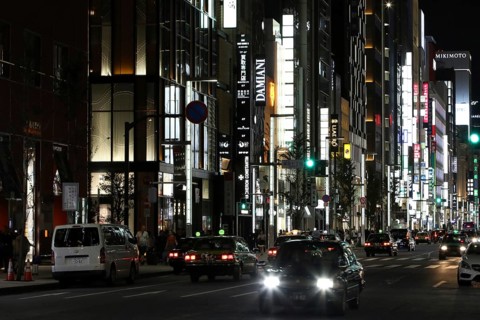 Illuminated street with neon lights and cars in traffic in Ginza district