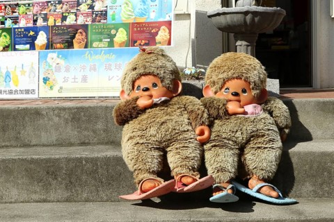 Two large Monchichi puppets on the stairs in front of a souvenir shop