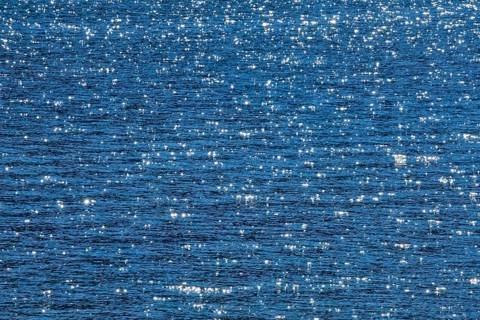 Sunbeams reflect glittering on the water surface of the Vierwaldstaettersee and form an abstract pattern