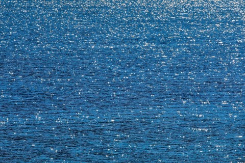 Sunbeams reflect glittering on the water surface of the Vierwaldstaettersee and form an abstract pattern