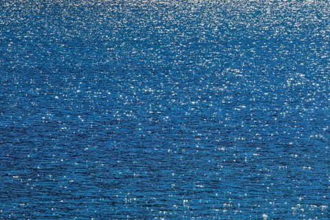 Sunbeams reflect glittering on the water surface of the Vierwaldstaettersee and form an abstract pattern
