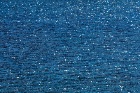 Sunbeams reflect glittering on the water surface of the Vierwaldstaettersee and form an abstract pattern