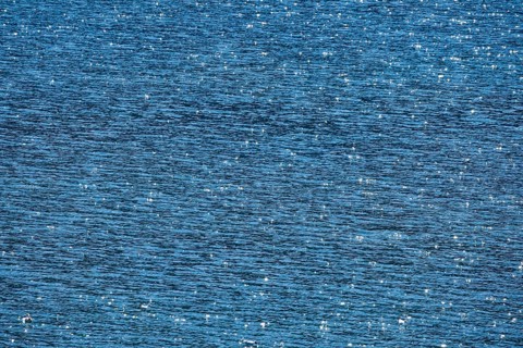 Sunbeams reflect glittering on the water surface of the Vierwaldstaettersee and form an abstract pattern