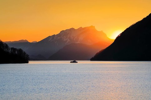 View from Brunnen on a boat on the Vierwaldstaettersee with Pilatus in the background at sunset