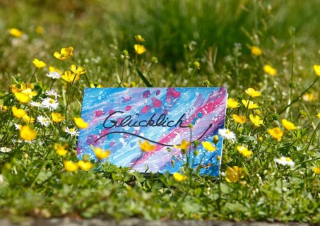 Self painted greeting card lies on flower meadow