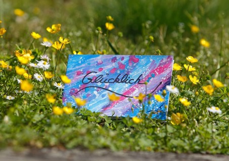 Self painted greeting card lies on flower meadow