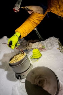 Man cooking with a camping stove in the snow