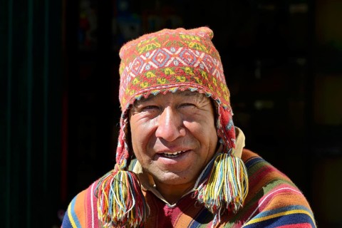 Indigenous man in colorful poncho and cap