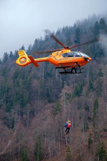 Two flight rescuers of the Bavarian Mountain Rescue Service hang on the wire rope of the rescue helicopter Christoph 14