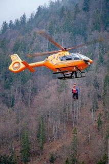 Two flight rescuers of the Bavarian Mountain Rescue Service hang on the wire rope of the rescue helicopter Christoph 14